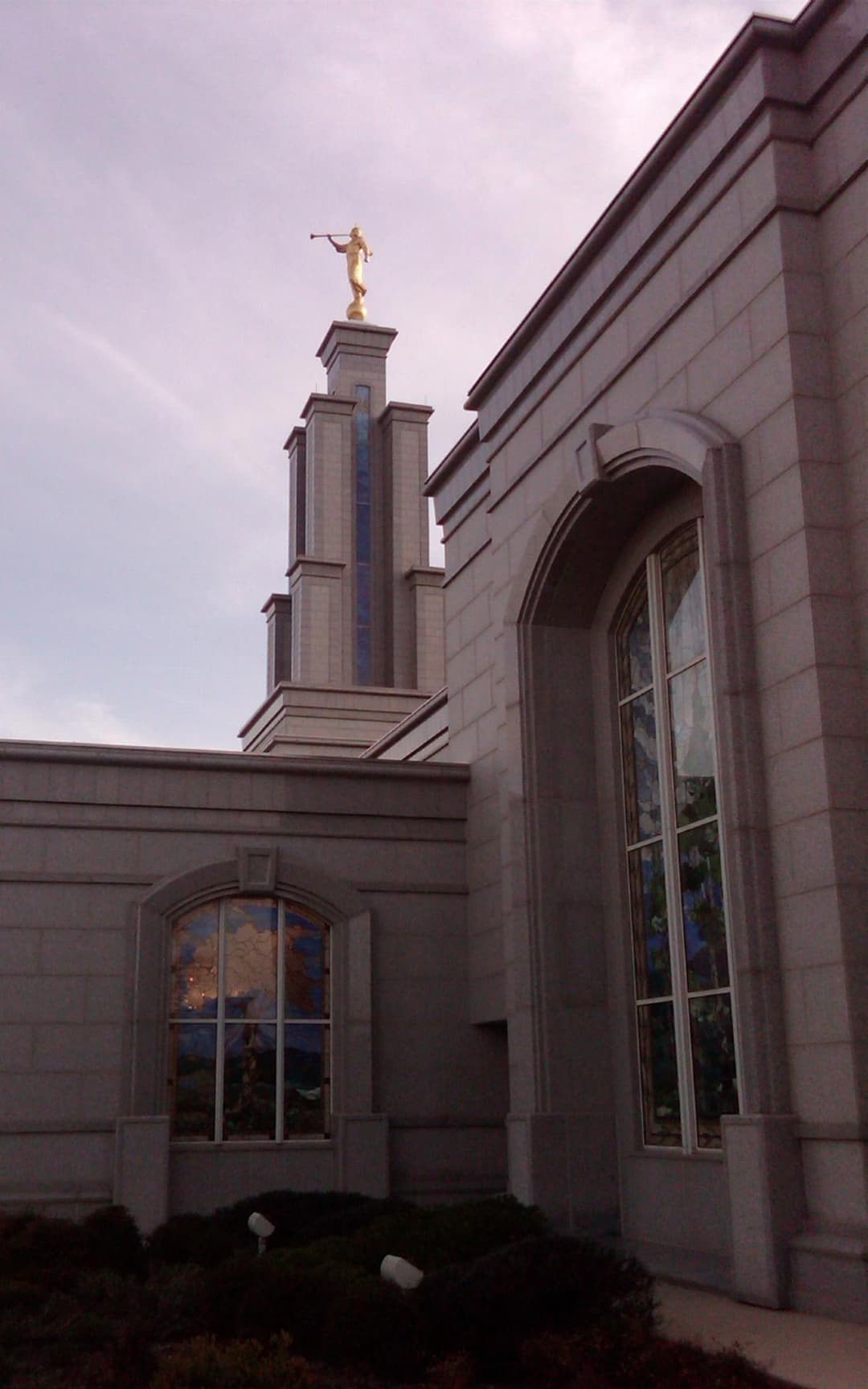 Low-angle view of the spire and stained-glass windows at twilight.