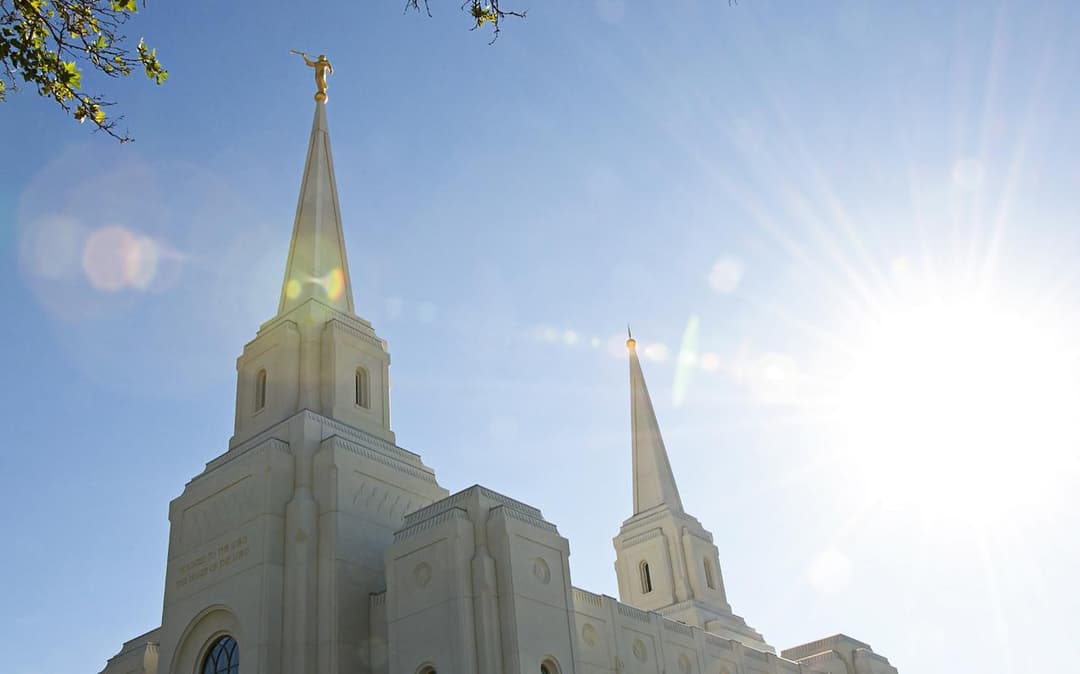 The majestic east facade of the Brigham City Utah Temple framed by summer foliage.
