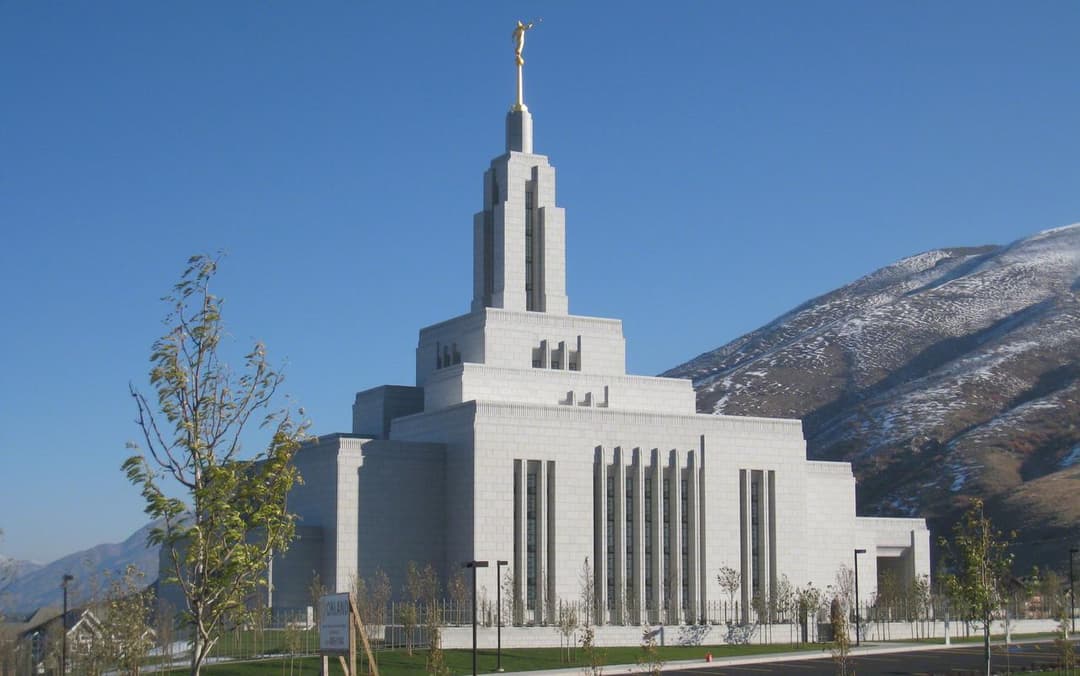 Draper Utah Temple, Angel Moroni, snow-dusted mountains, clear blue sky.