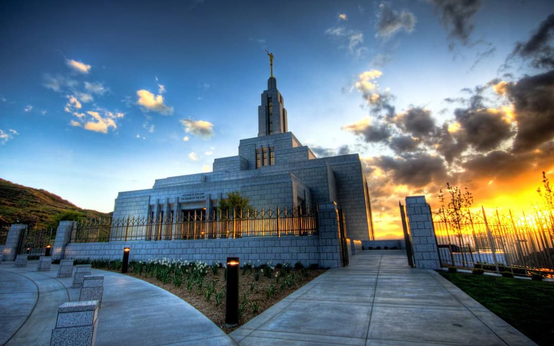 Draper Utah Temple exterior at dramatic sunset with Angel Moroni.