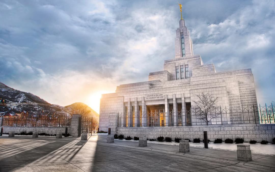 Draper Utah Temple exterior at sunrise, showing front entrance, spire, and Angel Moroni.