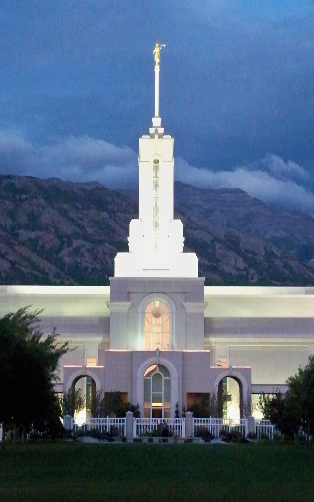 Mount Timpanogos Utah Temple central spire and facade illuminated at twilight.