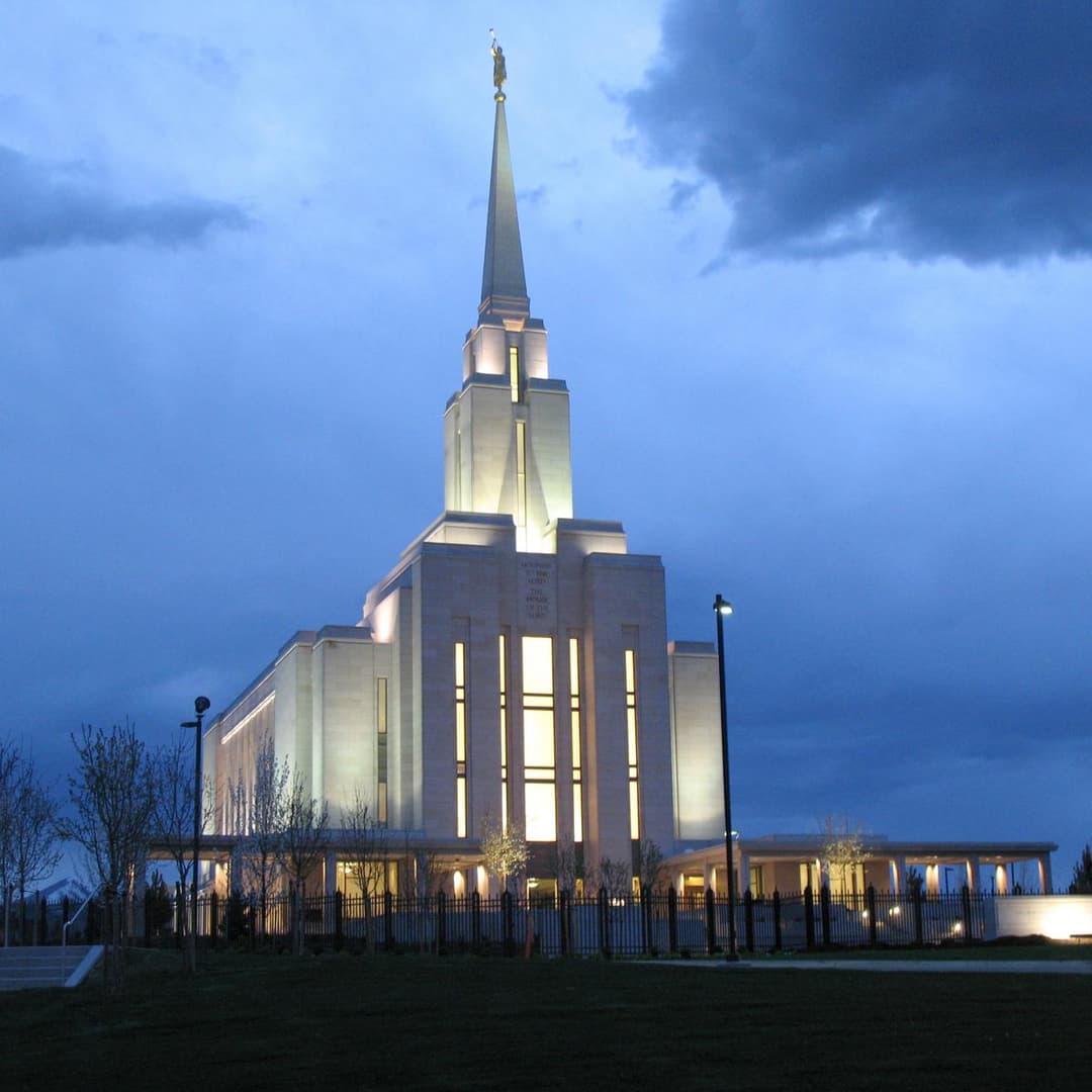 Low-angle view of the illuminated temple and spire at twilight.