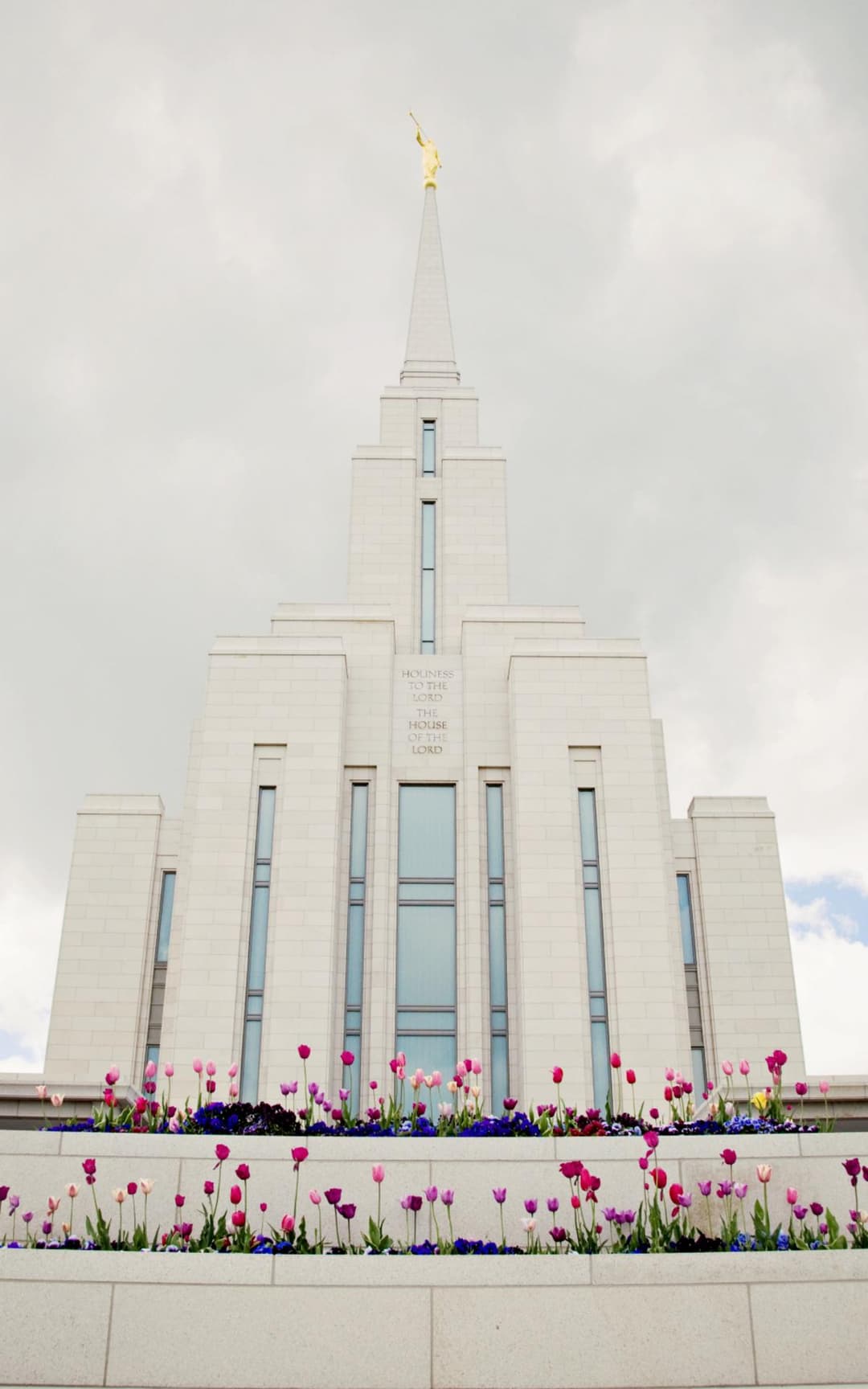 Low-angle front view of the single spire framed by colorful spring tulips.