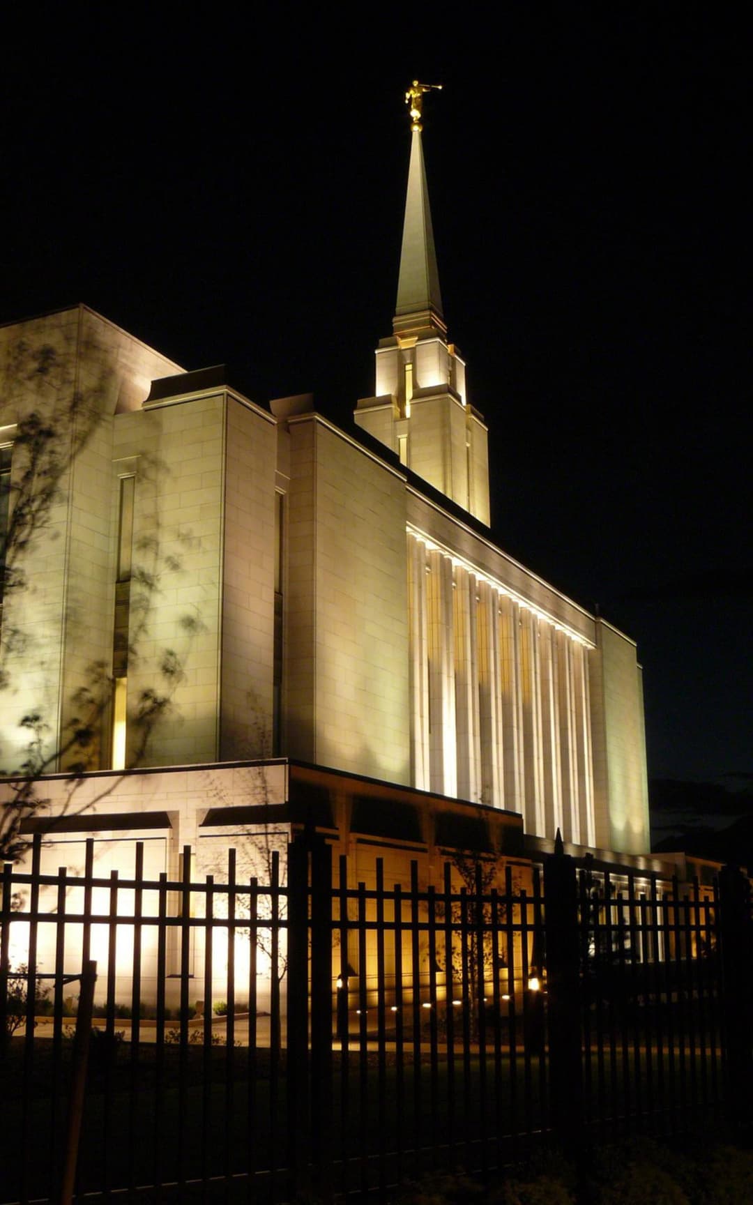 Low-angle night view of the illuminated temple exterior and spire.