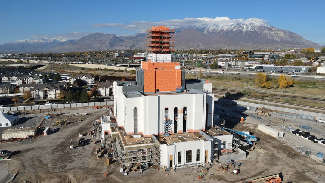 Aerial view of the Orem Utah Temple under construction with mountain backdrop.