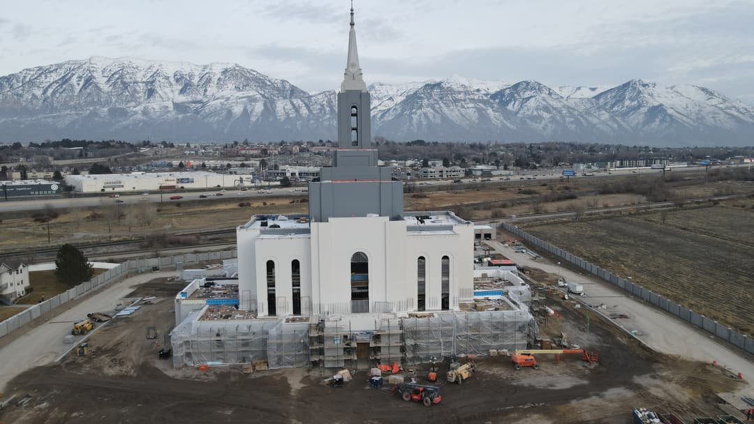 Aerial view of the Orem Utah Temple under construction with snowy mountains.
