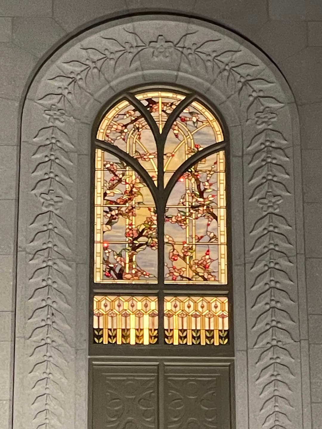 Stained glass window framed by carved stone inside the Orem Utah Temple.