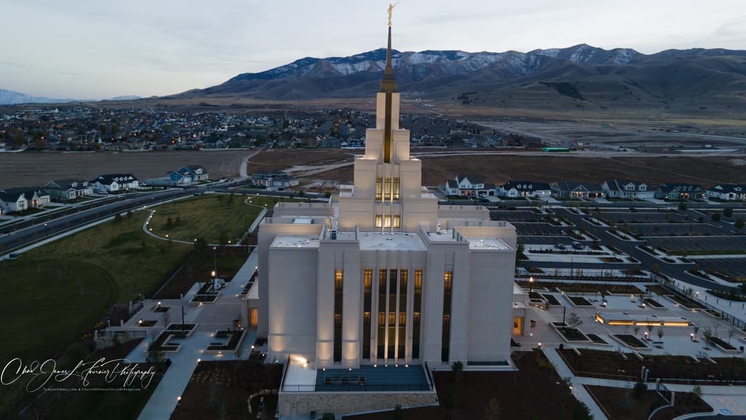 Aerial view of the illuminated Saratoga Springs Utah Temple at twilight.