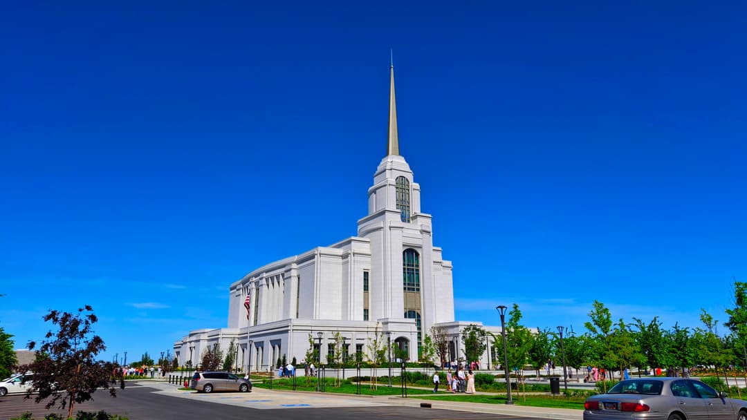 Wide-angle daytime view of the Syracuse Utah Temple under a clear blue sky.