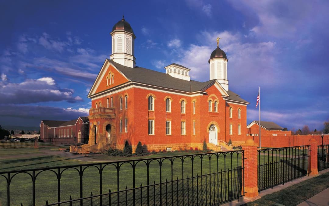 Angled exterior of the red brick Vernal Utah Temple at golden hour.