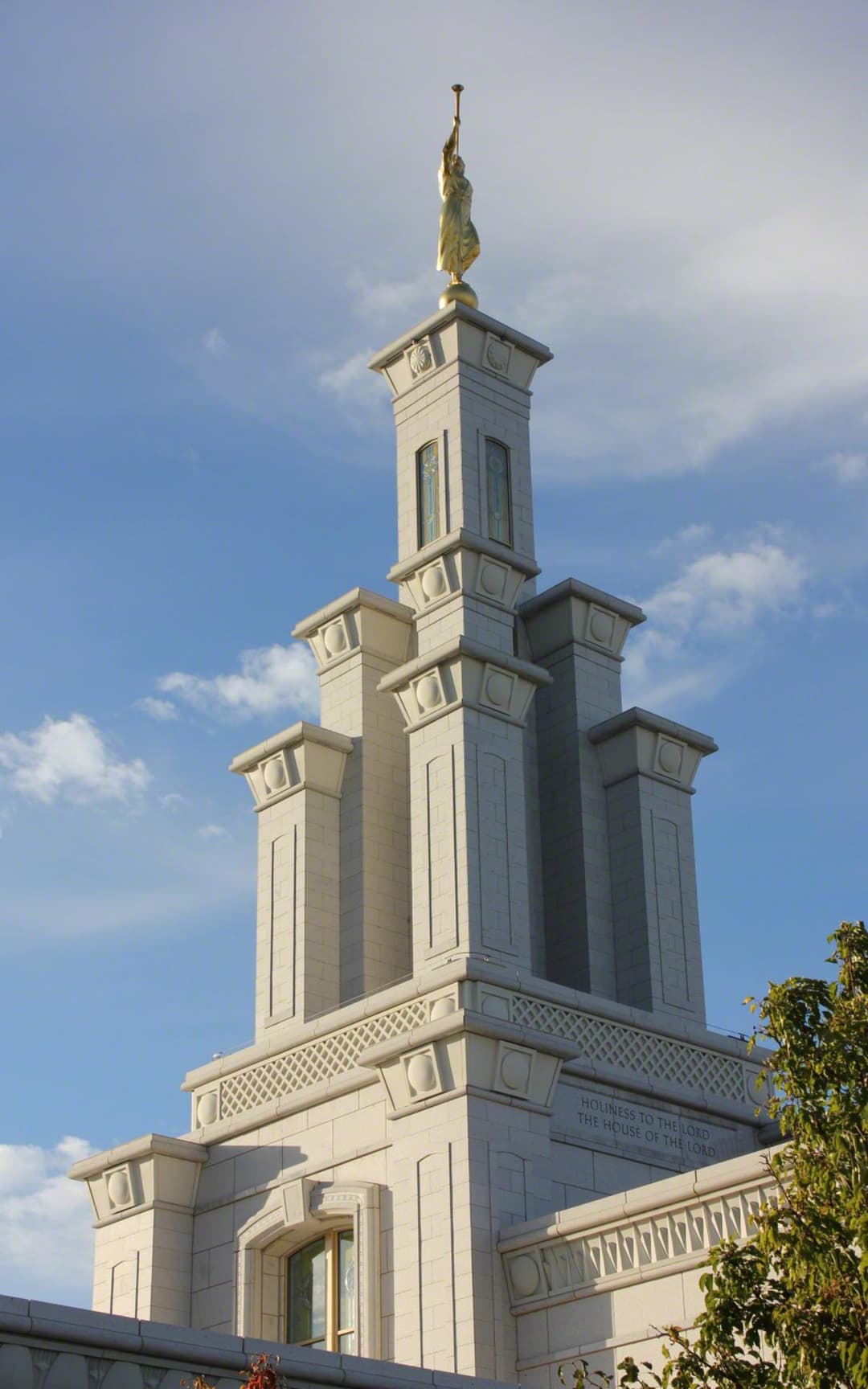 Low-angle daytime view of the temple spire and Angel Moroni statue.