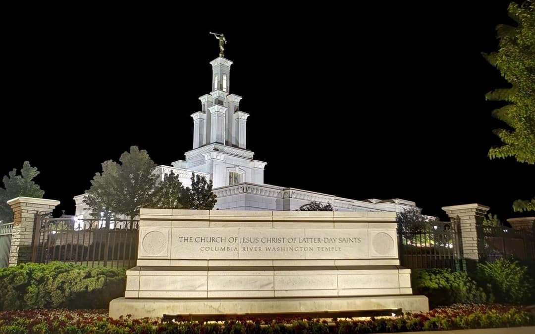 Columbia River Washington Temple sign and spire illuminated at night.