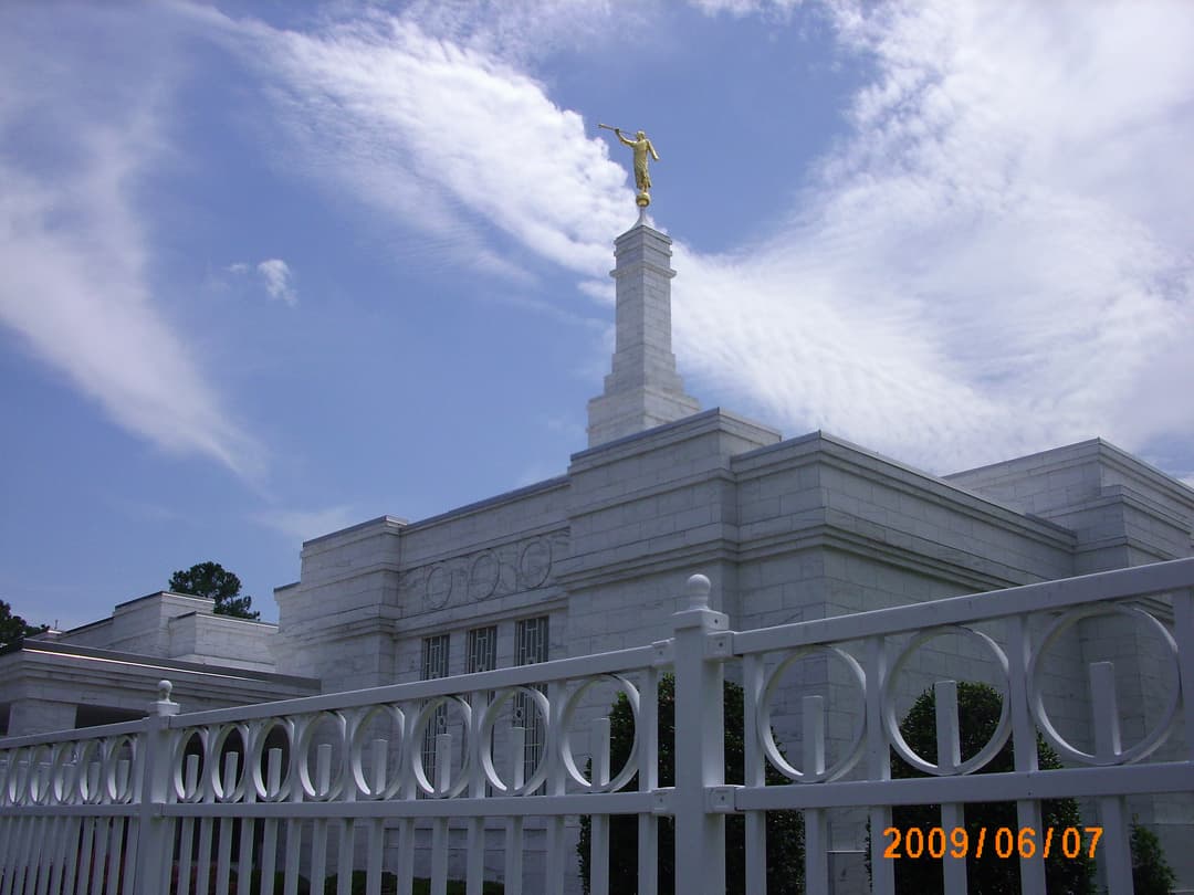 Low-angle view of the Spokane Washington Temple spire behind a white fence.