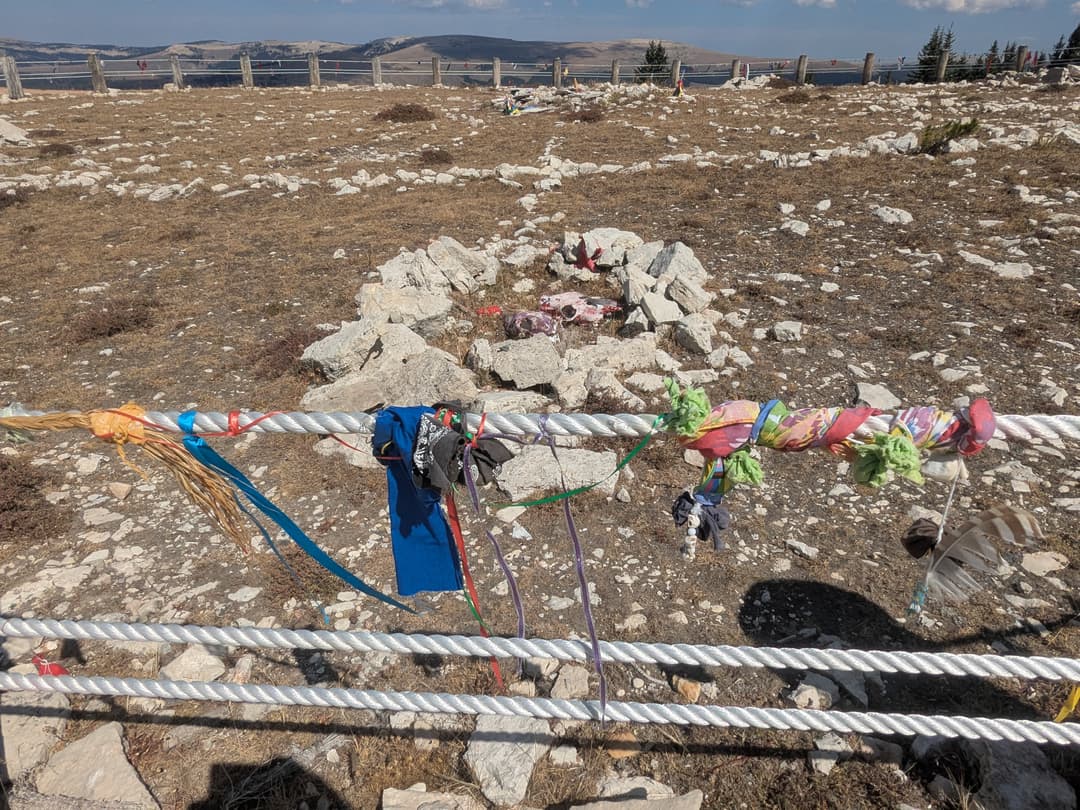 Prayer offerings on perimeter fence overlooking a stone cairn
