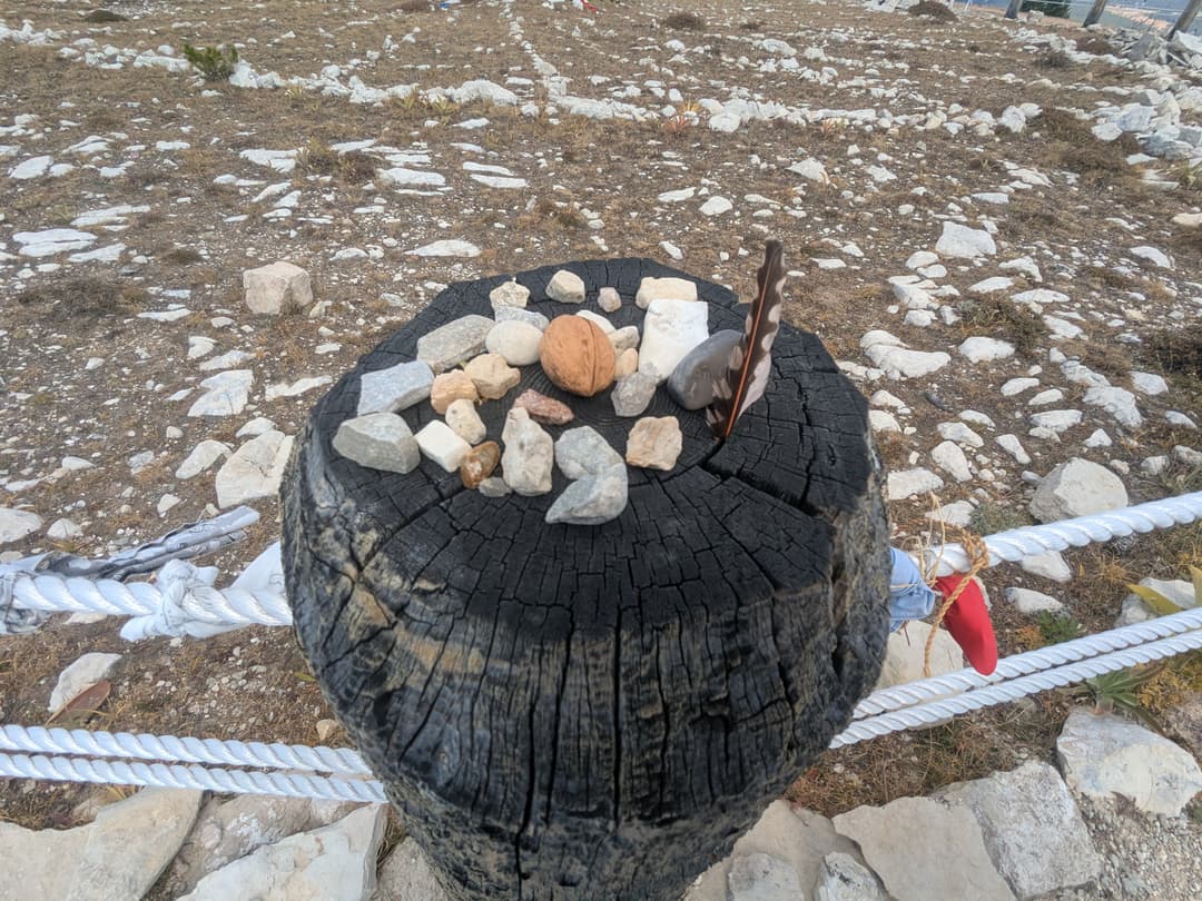 Offerings of stones and a feather atop a fence post at the Medicine Wheel.