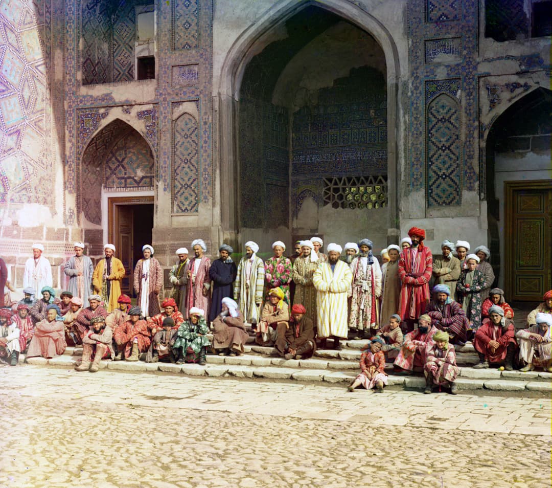 Local men in traditional robes before a madrasa portal in the Registan