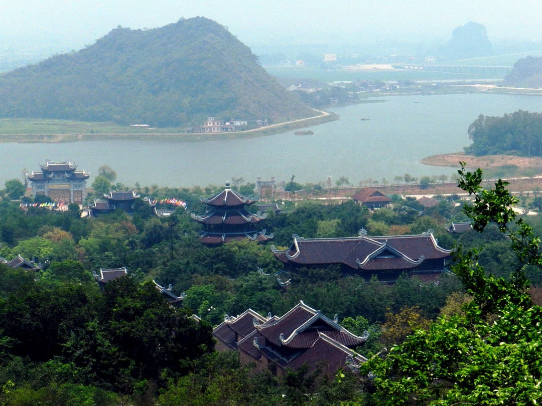 Elevated view of the Bái Đính Temple complex, lake, and mountain landscape.
