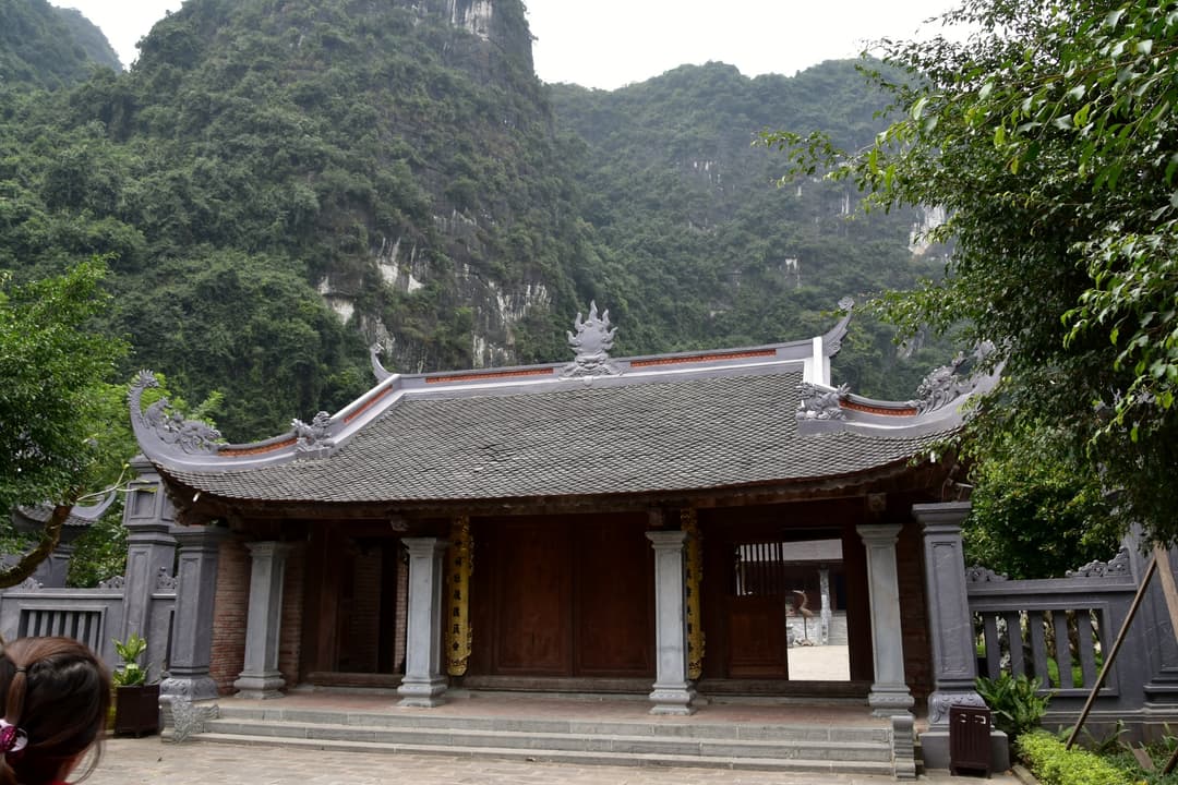 Front view of a traditional temple building set against karst mountains.