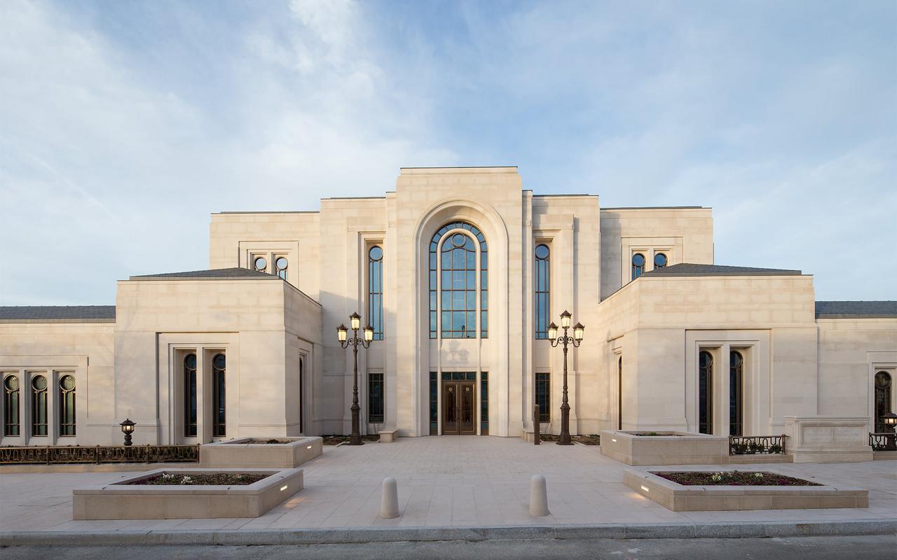 The Paris France Temple exterior showcasing warm Portuguese limestone and formal landscaping.