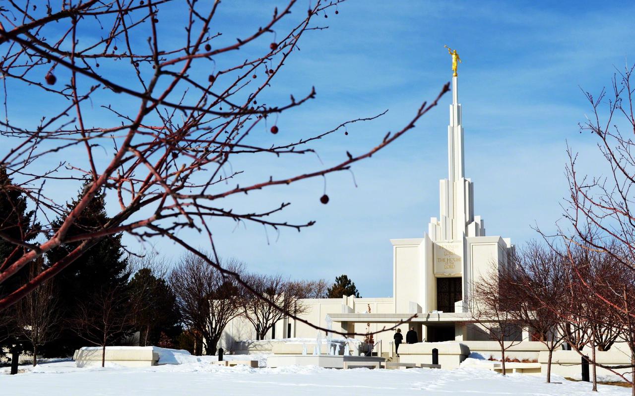 The Denver Colorado Temple glowing against a Colorado sunset, its single spire reaching skyward.