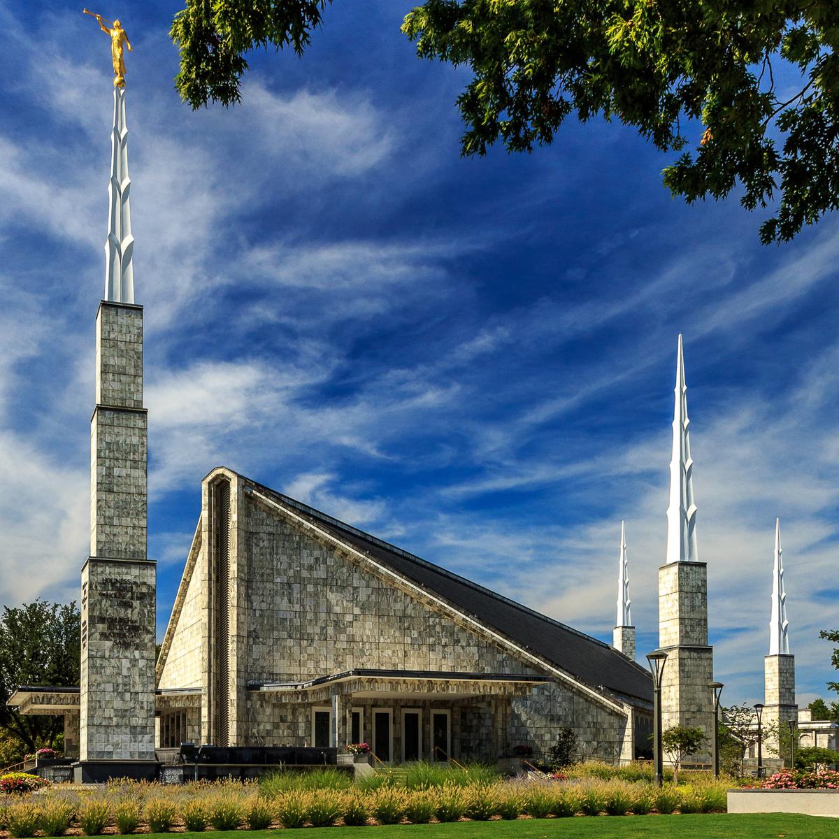 The Angel Moroni statue atop the tallest spire, gilded in gold leaf against a blue Texas sky.